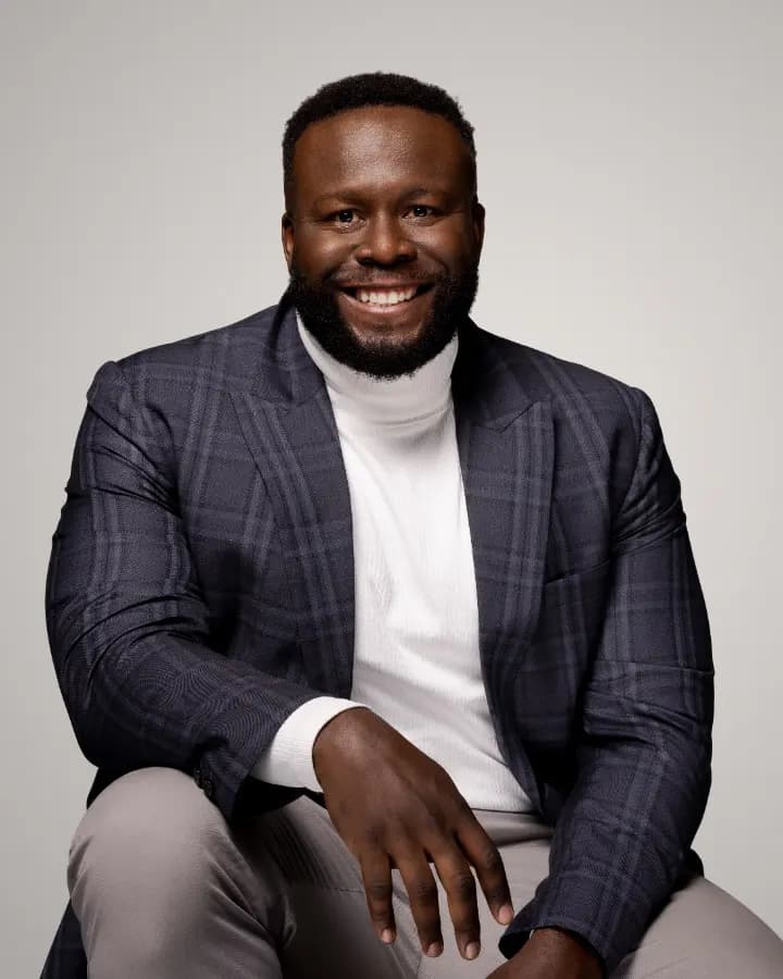 Perry Chuinkam, smiling, in a navy plaid blazer and white turtleneck